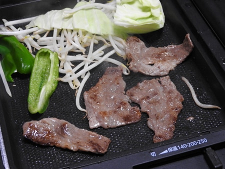 強火で肉と野菜を焼いている画像